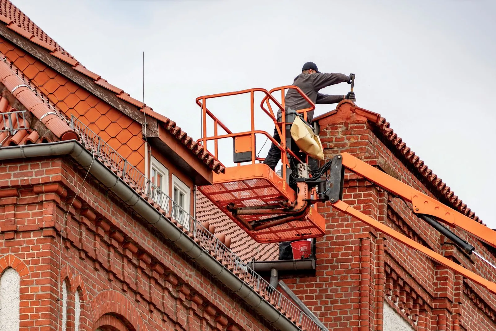 Roofer carrying out general maintenance and moss clearance on a roof