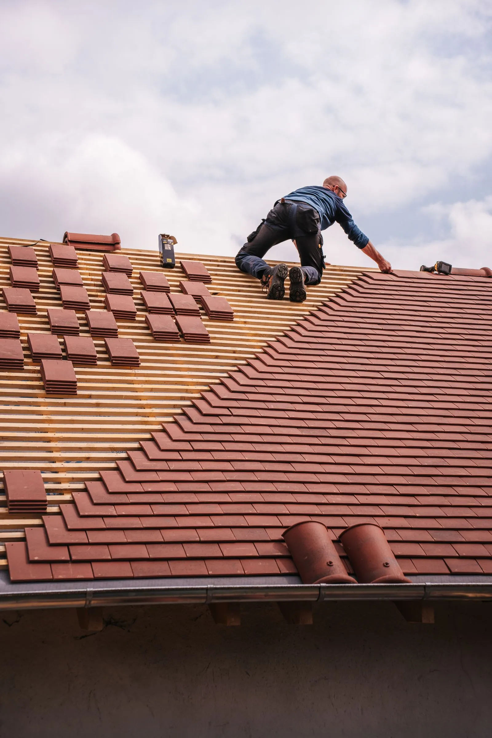 Roofer replacing slate tiles on a pitched roof